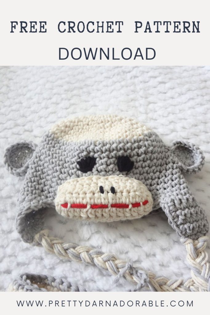 Gray and cream crocheted sock monkey hat with ears and braids on white textured surface; text: "Free crochet sock monkey hat pattern download. Free crochet pattern