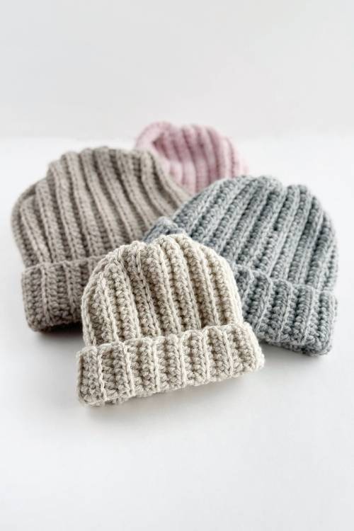 Four ribbed beanies in cream, light gray, medium gray, and pale pink overlap on a white surface; no text or promo shown. Free crochet pattern