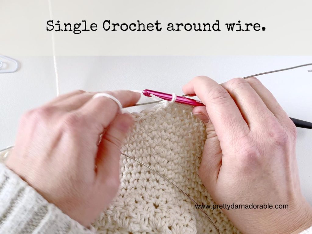 two hands crocheting around a wire