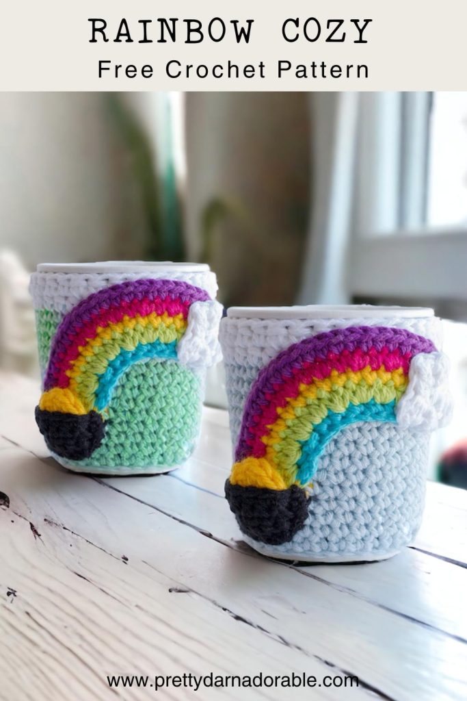 2 Crochet cup cozies with rainbow with cloud on one side and pot of gold on the other