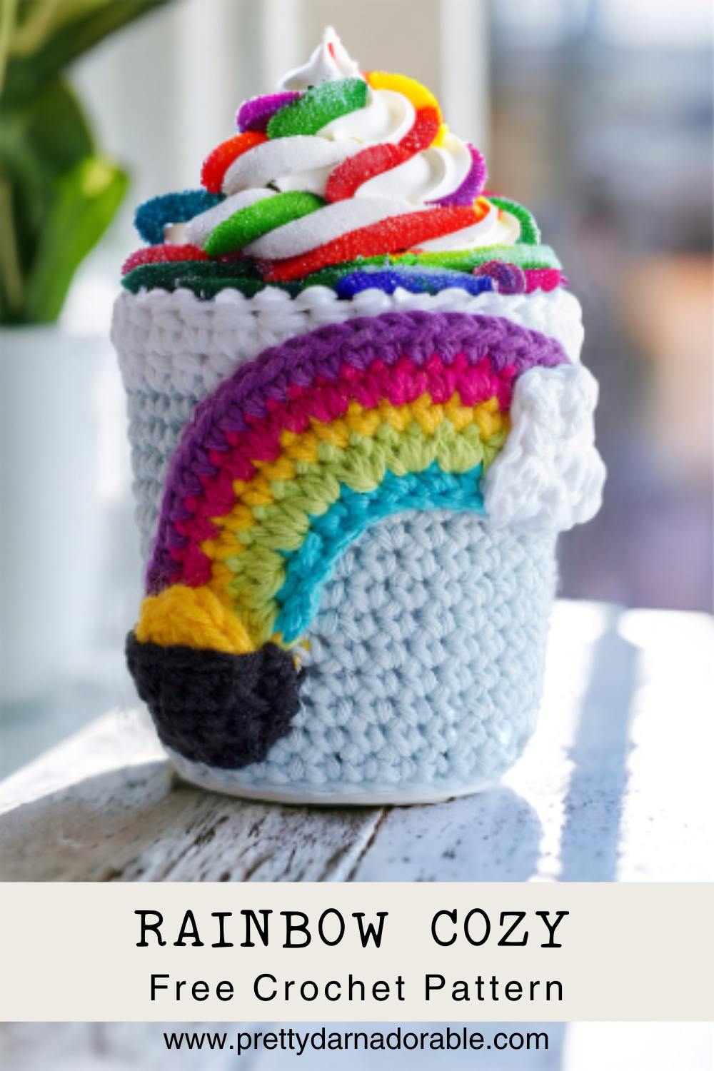 Crochet cup cozy with rainbow with cloud on one side and pot of gold on the other