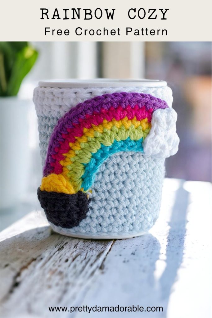 Crochet cup cozy with rainbow with cloud on one side and pot of gold on the other
