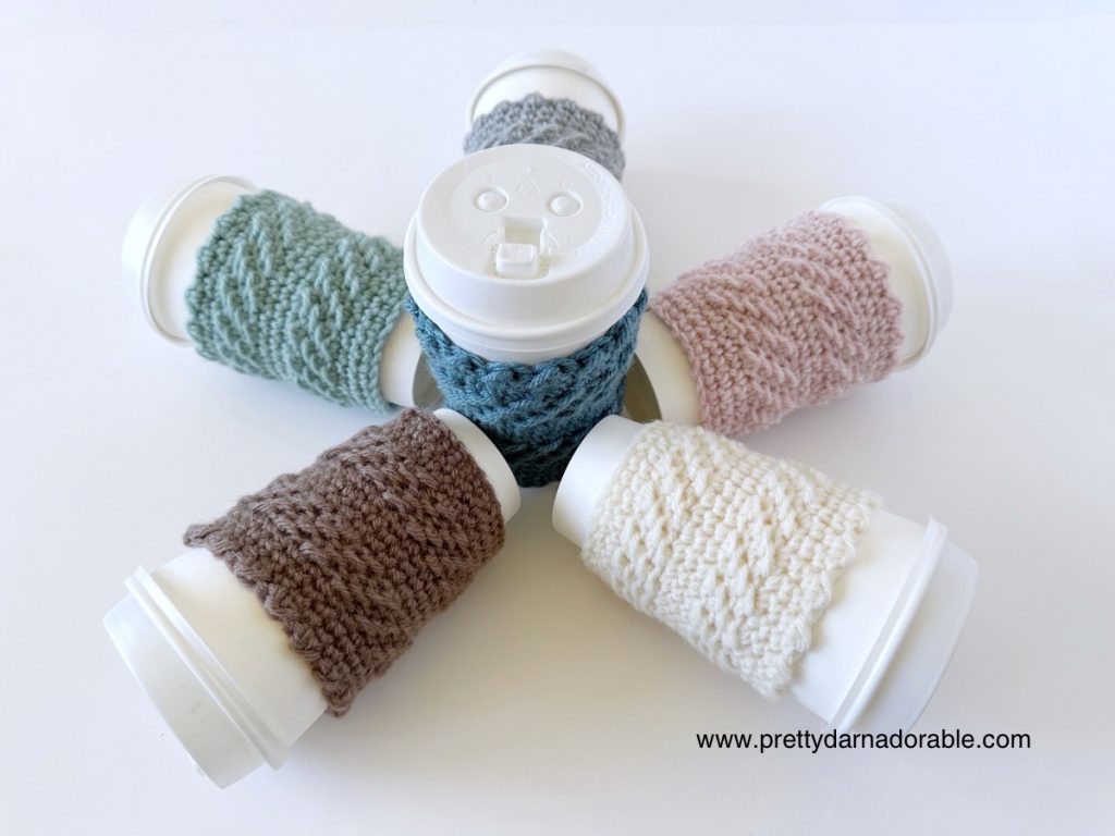 6 cups laying on their side with coloured crochet cup cozies