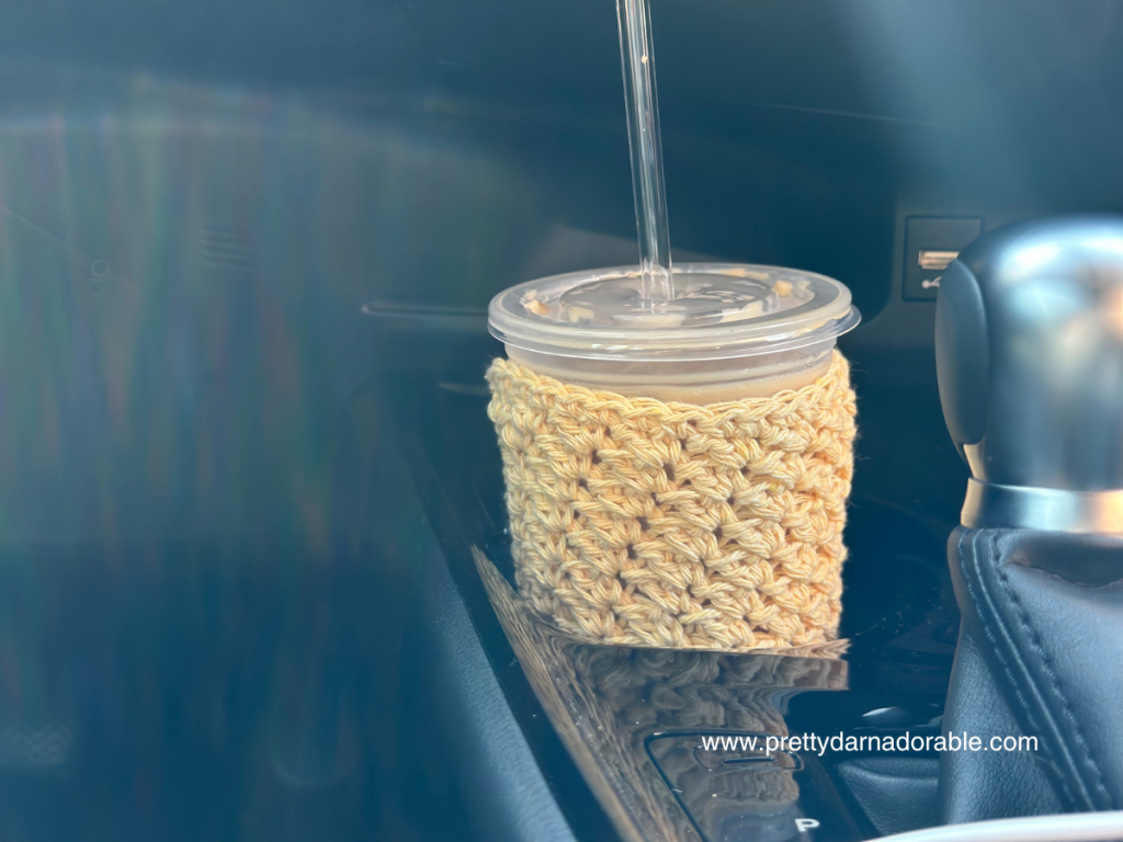 Textured crochet cup cozy with bottom in a cup holder in a car