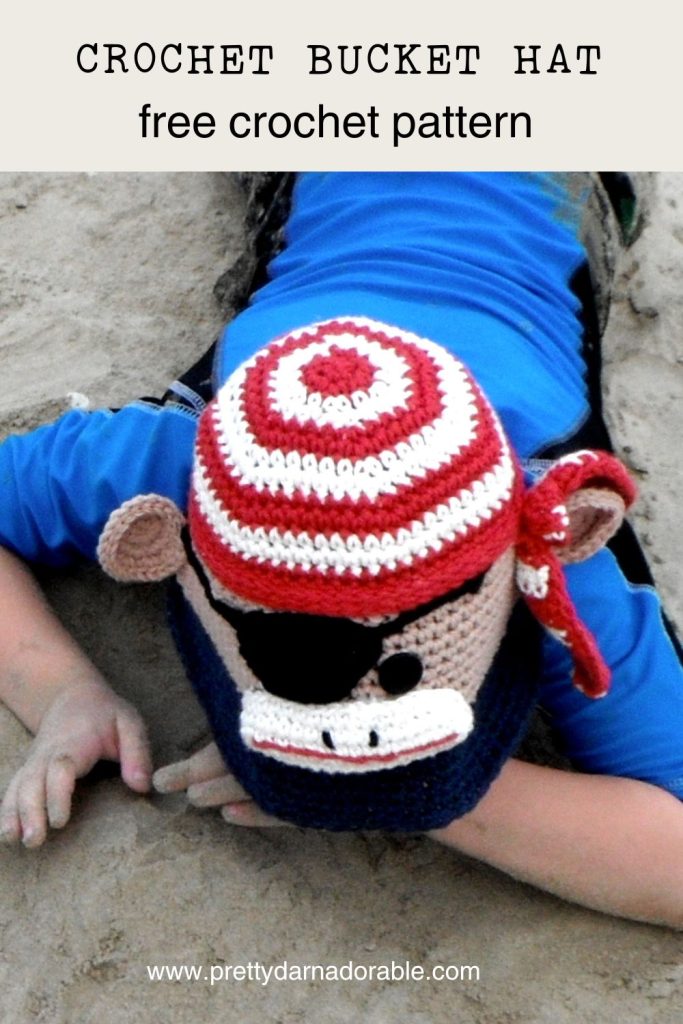 crochet bucket hat that looks like a pirate sock monkey made from red white and blue the monkey has an eye patch too. Free crochet bucket hat pattern.