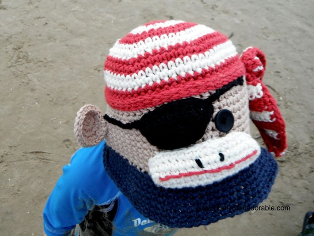 crochet bucket hat that looks like a pirate sock monkey made from red white and blue the monkey has an eye patch too. Free crochet bucket hat pattern.