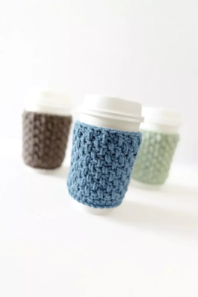 a group of crochet coffee cozies in soft pastel colours