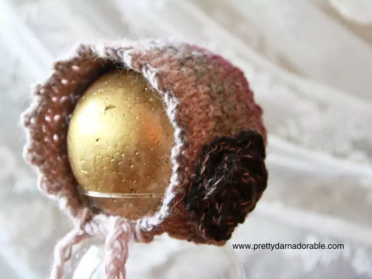 a crochet baby bonnet with a rose in pink and purple