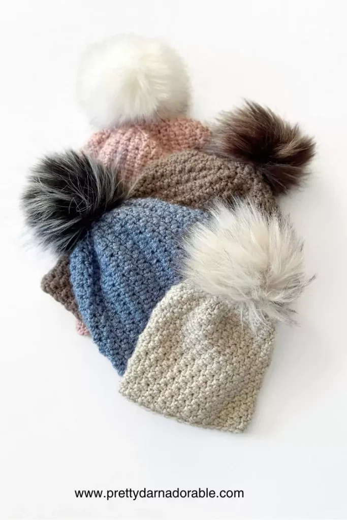 a group of crochet slouch hats with pom poms