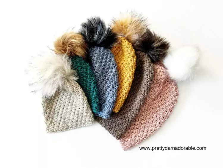 a group of crochet slouch hats with pom poms