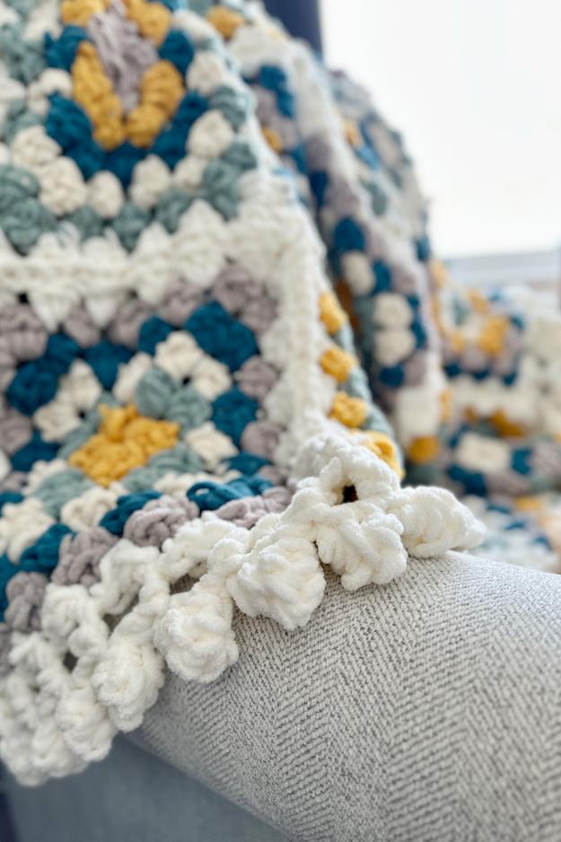 chunky granny square blanket with bobble edging on chair
