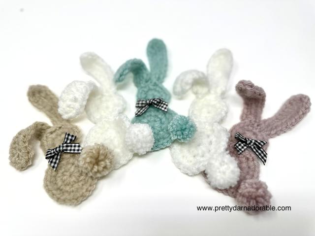 a little herd of crochet bunnies in beige blue white and pink