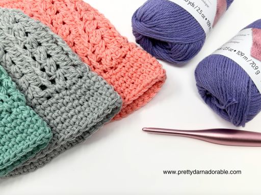 three crocheted hats with yarn and a crochet hook