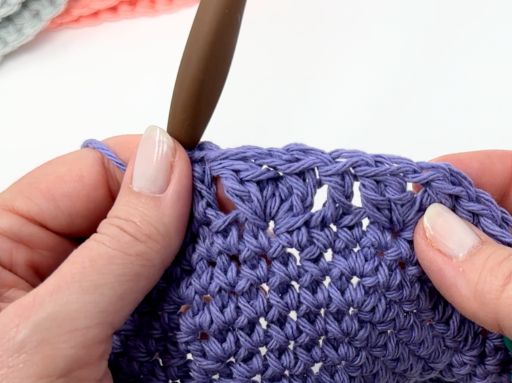 a person is using a crochet hook to make a crocheted piece