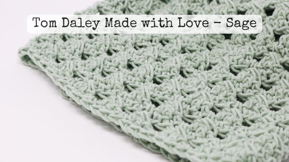 A close-up of a sage green crochet fabric with a textured, open pattern, perfect for crafting a simple granny stitch crochet beanie. Text overlay reads: Tom Daley Made with Love – Sage.