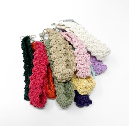A collection of crocheted keychains or wristlets in various colors showcases unique crochet keychain patterns, all artfully arranged overlapping on a white background.