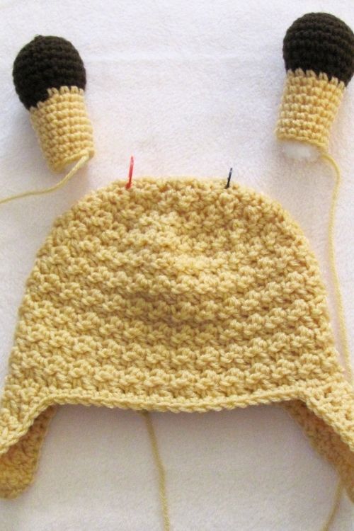 Crocheted yellow hat with brown and giraffe hat, shown on a plain white surface. No visible text. Free crochet pattern