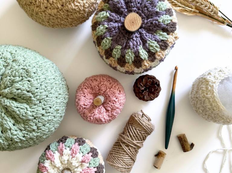 Pastel crocheted rounds, green crochet hook, twine, pine cone, wood buttons, corks, and dried grasses on a white surface. Free crochet pattern