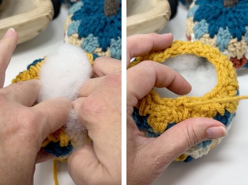 Hands fill a small, round crocheted item with white stuffing; it has a yellow rim and multicolored body for a pumpkin craft.