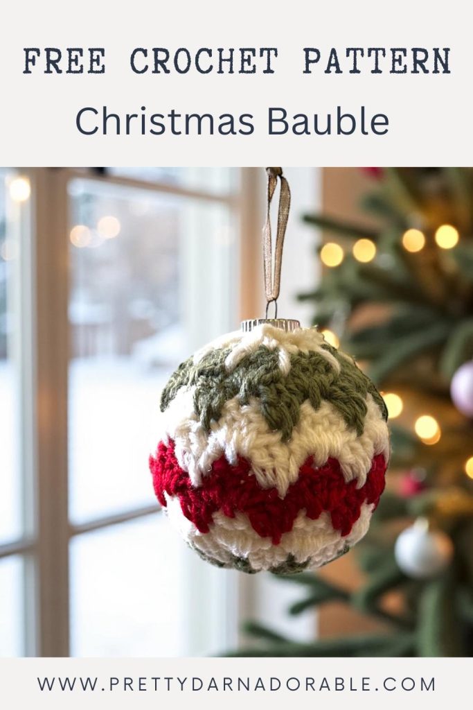 A red, green, and white crocheted Christmas bauble hangs before a decorated tree; text says “Free Crochet Pattern Christmas Bauble.”. Free crochet pattern