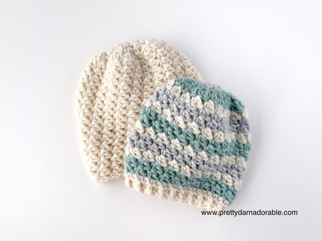 Two crocheted baby hats on a white surface—one solid cream, one striped cream, gray, and teal. Free Easy Crochet Slouch Hat Pattern
