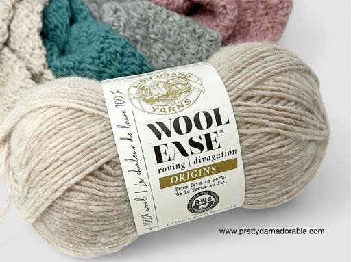 A light beige skein of Lion Brand Wool-Ease Origins roving yarn with swatches in cream, teal, and gray behind; label visible. Free crochet pattern