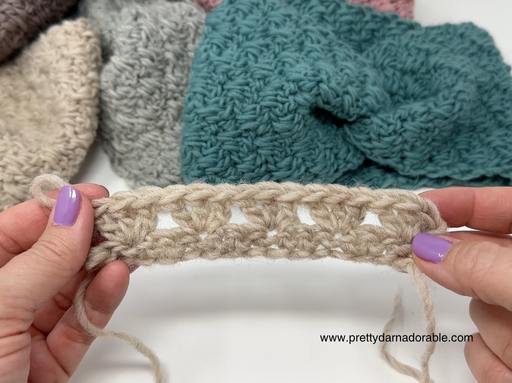 Hands with lavender nail polish hold a beige crochet swatch; cream, gray, and teal crocheted pieces behind. www.prettydarnadorable.com in corner. Free crochet pattern