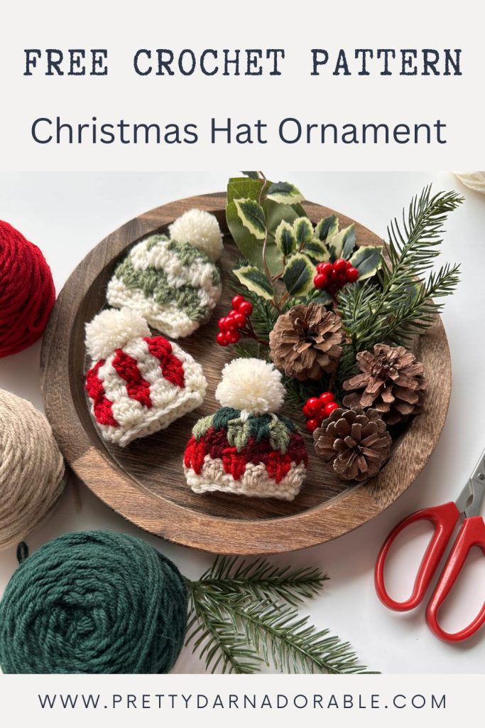 A wooden tray with pine cones, pine and holly sprigs, and three crocheted Christmas hat ornaments; promo text: Free crochet pattern—Christmas Hat Ornament. Free crochet pattern