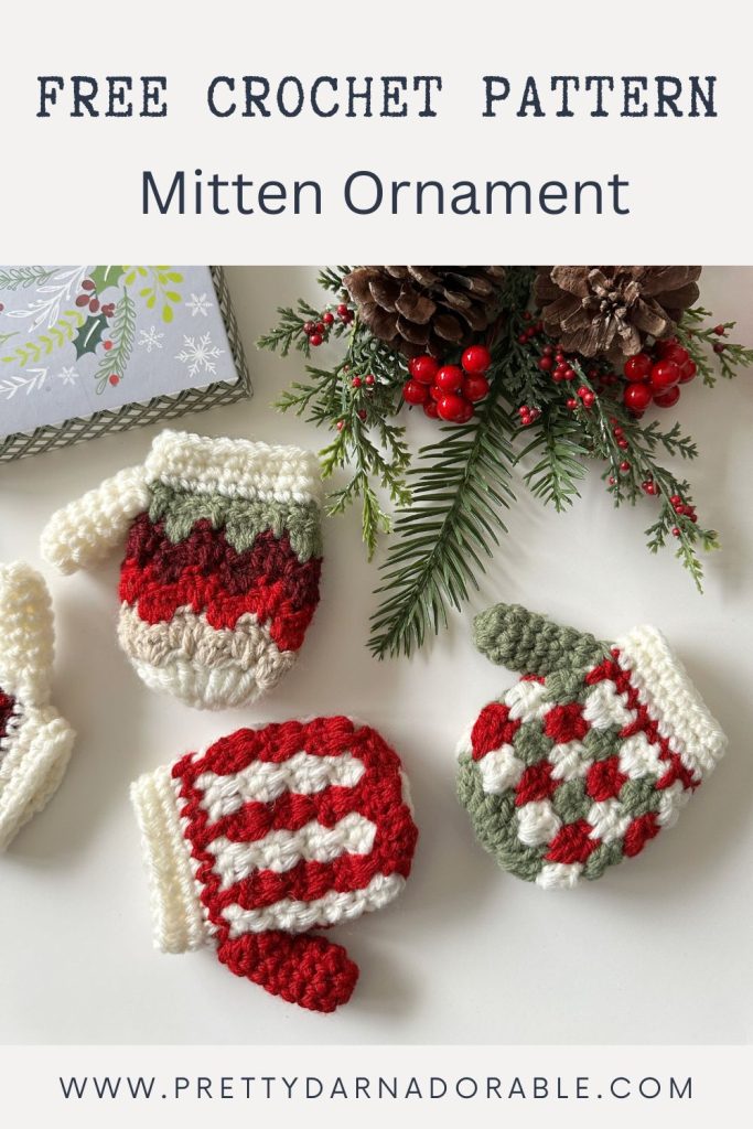 Red, white, and green crocheted mitten ornaments with holiday decor and a gift box; text: Free crochet pattern Mitten Ornament. Free crochet pattern