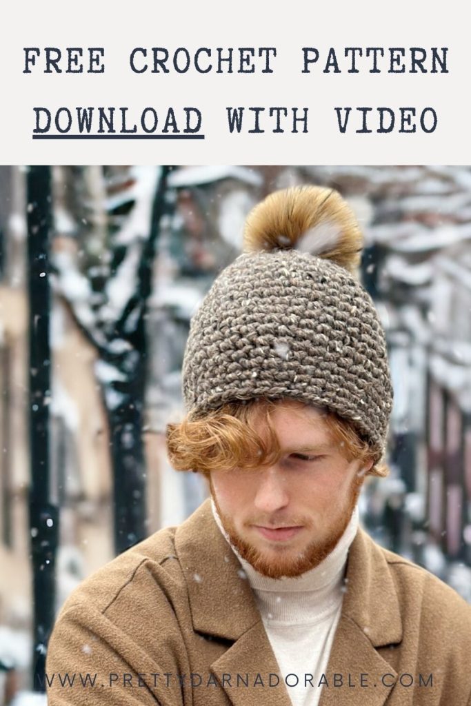 Man with reddish beard in chunky crocheted hat with fur pom-pom outdoors in snow; text: Free crochet pattern download with video. Free crochet pattern