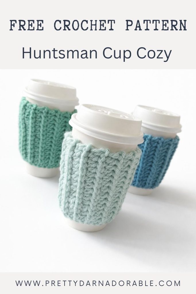 Three takeaway cups with white lids, each with ribbed, blue or green crocheted cozies. Text: “Free Crochet Pattern Huntsman Cup Cozy.” Website link below. Free crochet pattern