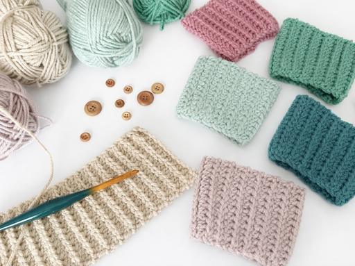 Yarn balls, wooden buttons, a crochet hook, and pastel crochet swatches in pink, green, blue, cream, and purple on white. Free crochet pattern