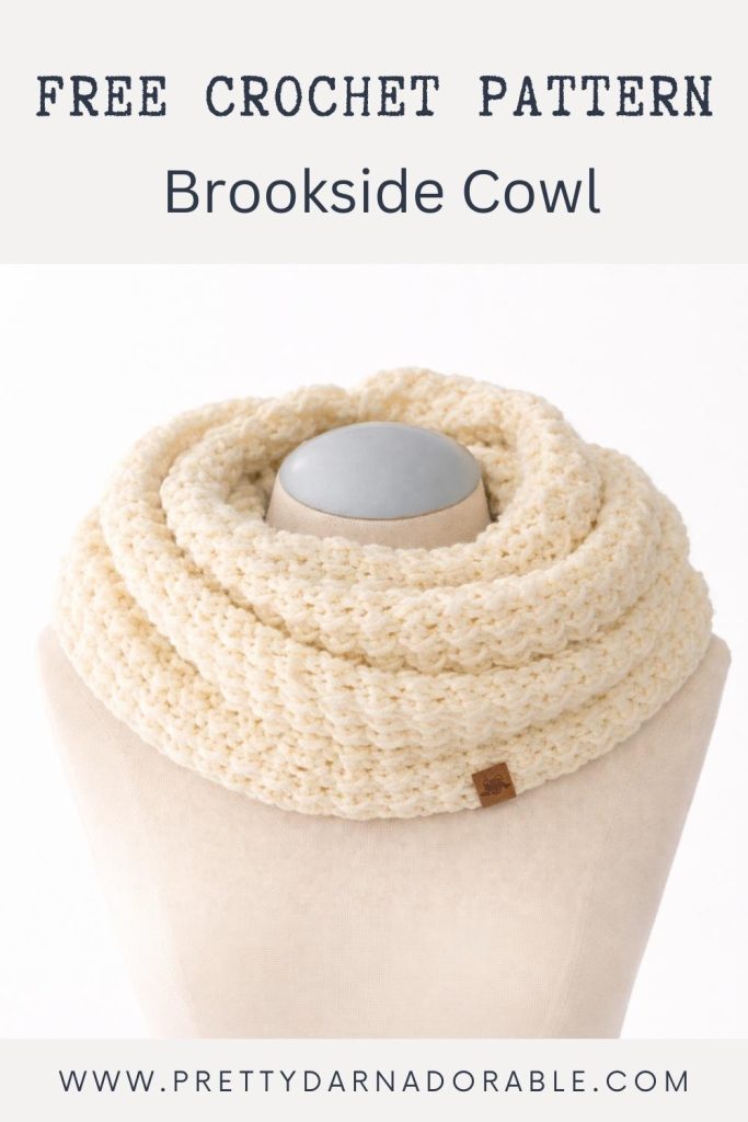 Cream crochet cowl displayed on a mannequin; top text reads "Free Crochet Pattern Brookside Cowl," with www.prettydarnadorable.com below. Free crochet pattern