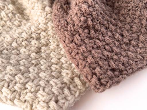Close-up of two thick, hand-made fabrics in cream and light brown colors with a prominent, textured stitch pattern overlapping. Free crochet pattern