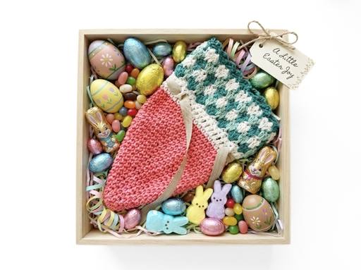 Wooden box with colorful Easter eggs, candy, marshmallow bunnies, and a carrot-shaped crochet pouch labeled “A little Easter joy.”. Free crochet pattern