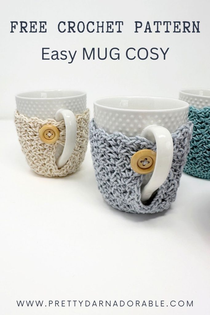 Three white mugs with crocheted cozies and wooden buttons sit on a white background. Text: Free Crochet Pattern: Easy Mug Cosy. Website prettydarnadorable.com appears below. Free crochet pattern