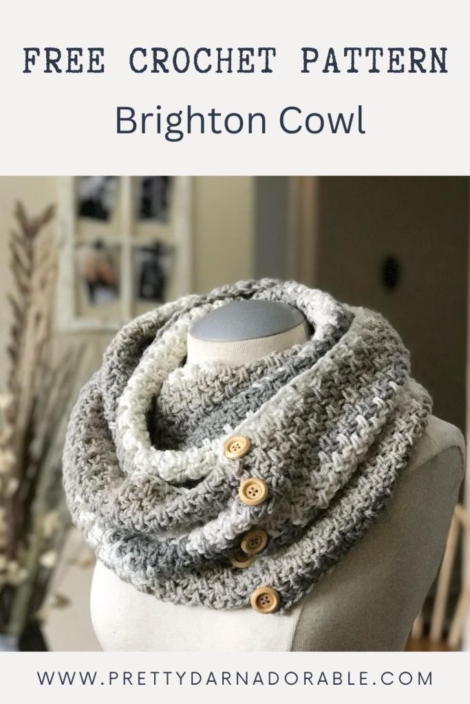 A chunky, neutral-colored crocheted cowl with wooden buttons is shown on a mannequin, with the text "Free Crochet Pattern Brighton Cowl" and a website URL at the bottom. Free crochet pattern