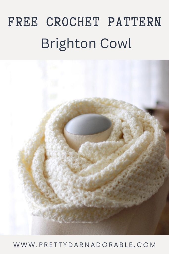 A cream-colored, textured crochet cowl is shown on a mannequin with the text "FREE CROCHET PATTERN Brighton Cowl" and the website "www.prettydarnadorable.com" displayed at the bottom. Free crochet pattern