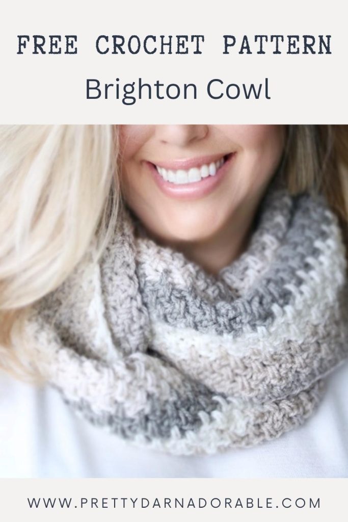 A smiling woman wears a thick, striped gray and white crochet cowl. Text on the image says, “Free Crochet Pattern Brighton Cowl,” with the website www.prettydarnadorable.com visible. Free crochet pattern