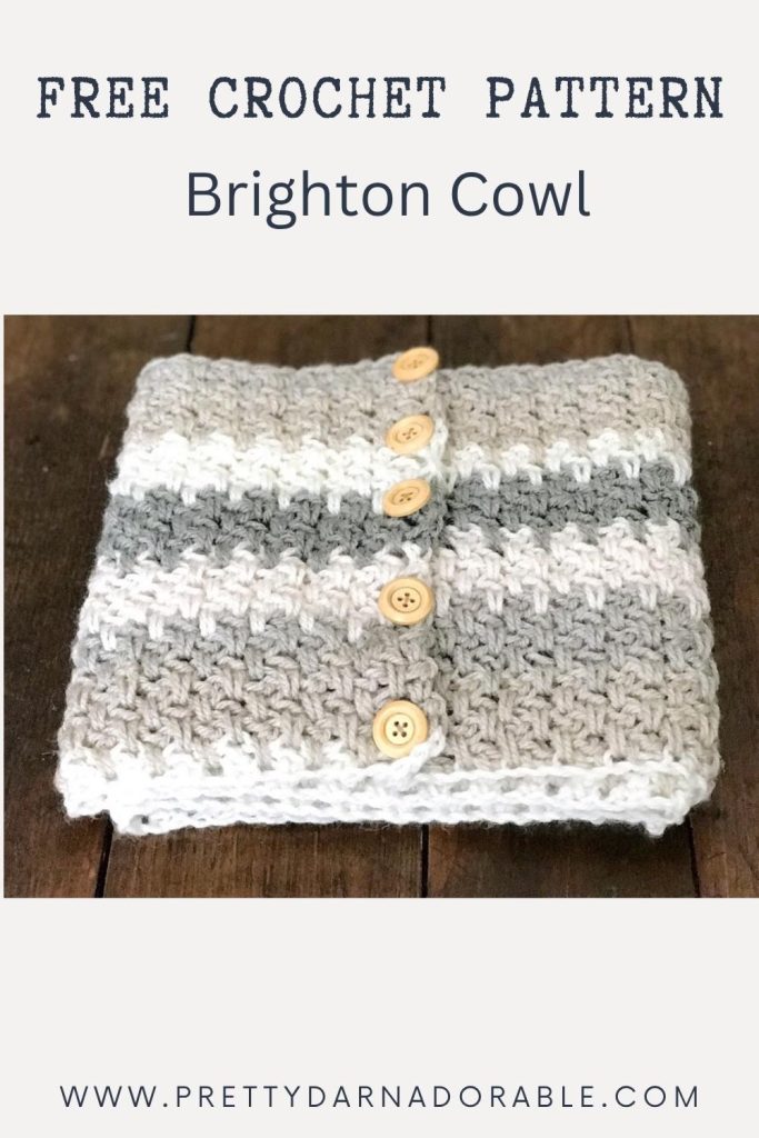 Folded crocheted cowl with gray, white, and light gray stripes and four wooden buttons; visible text says "Free Crochet Pattern Brighton Cowl" and "www.prettydarnadorable.com. Free crochet pattern