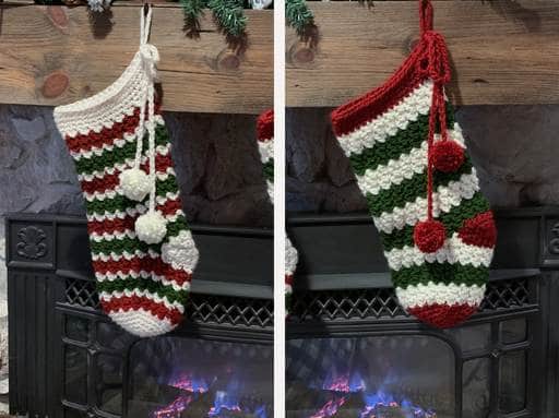 Two crocheted Christmas stockings with red, white, and green stripes hang above a fireplace; one stocking has white pom-poms, and the other has red pom-poms. Free crochet pattern